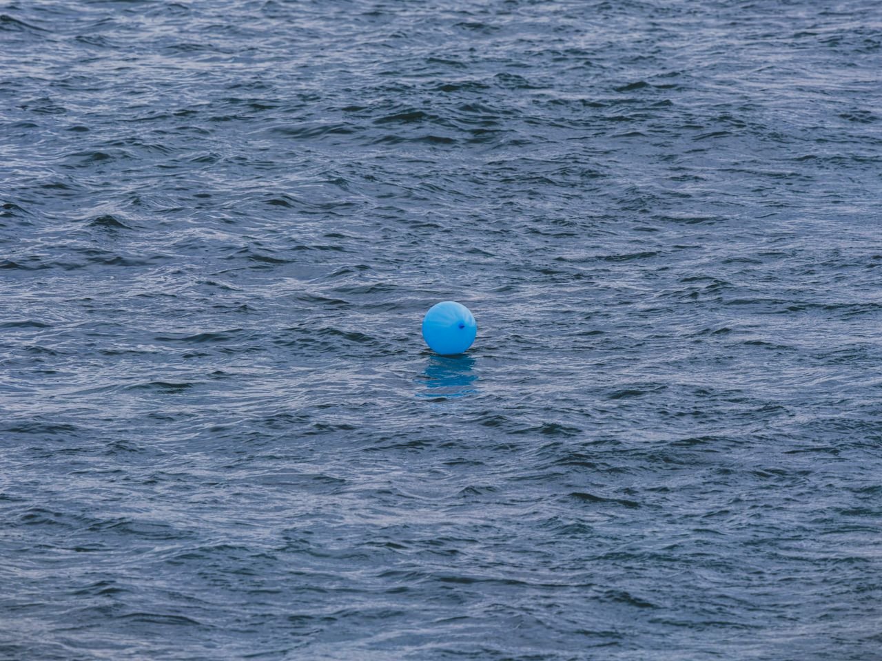 A lone blue balloon drifting on the ocean surface in Antalya, Türkiye.